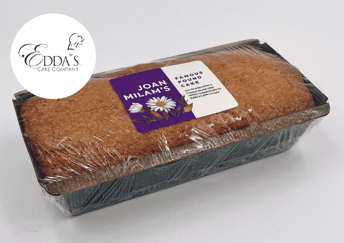 A loaf of Joan Milam's Famous Pound Cake, wrapped in plastic and labeled, sits on a white background. The Edda’s Cake Company logo is visible in the top left corner.