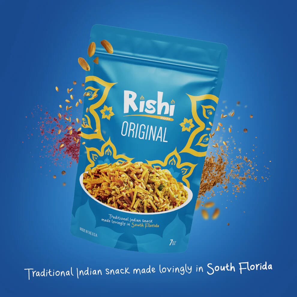 A blue pouch of Rishi Snacks Original Indian snack with yellow patterns and a photo of the snack, surrounded by scattered pieces, on a blue background. Text reads: Traditional Indian snack made lovingly in South Florida, supporting community empowerment.