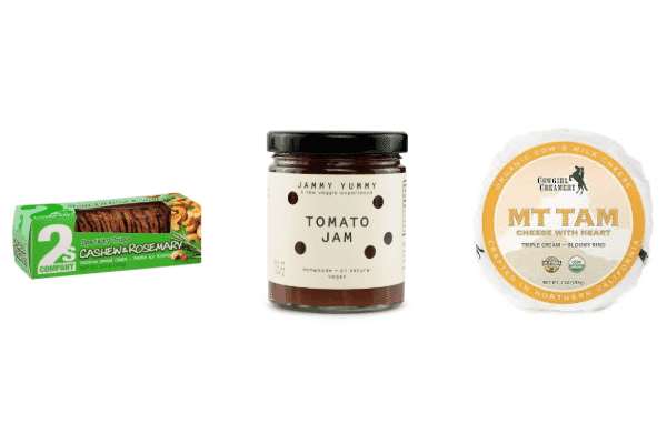 A package of rosemary cashew crisps, a jar of tomato jam, and a round of Cowgirl Creamery Mt Tam cheese displayed side by side on a white background—perfect for delicious cheese pairings.